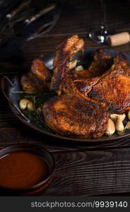 Juicy, slice of fried pork chop on a bone in oil with garlic and herbs in a pan. Close-up.