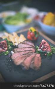 Juicy slices of grilled steak with vegetables on a wooden board. Juicy slices of grilled steak on wooden board