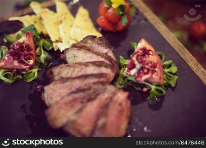 Juicy slices of grilled steak with vegetables on a wooden board. Juicy slices of grilled steak on wooden board