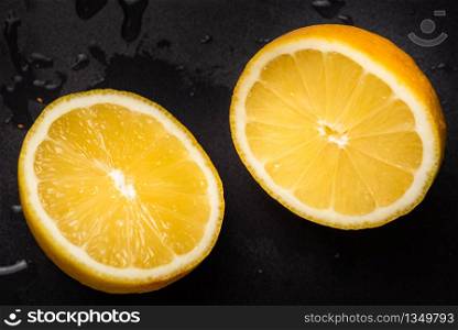 Juicy yellow lemon sliced in half on a black background isolated.. Juicy yellow lemon sliced in half on a black background isolated