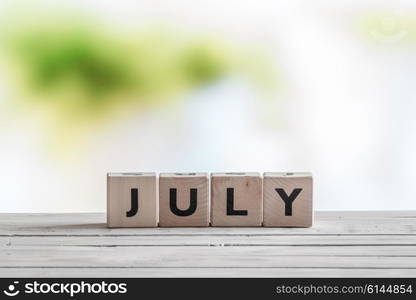 July sign on a wooden table in the nature