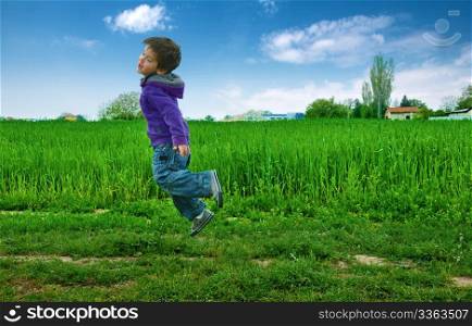 Jumped boy on green meadow, blue sky