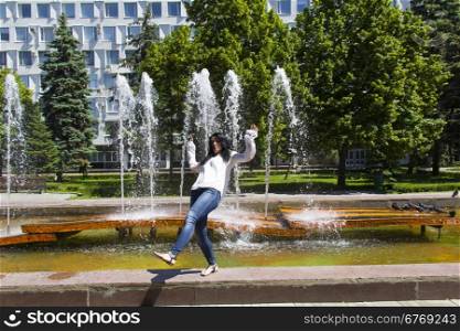 Jumping Caucasian brunette woman on fountain background
