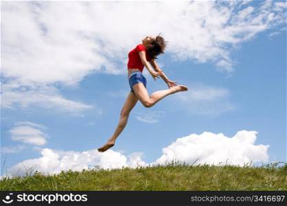 Jumping girl on the green meadow