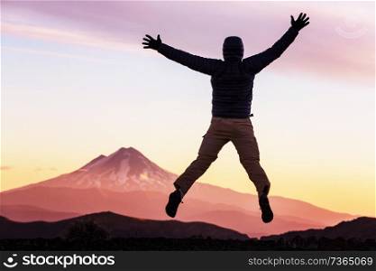 Jumping man in high mountains at sunset