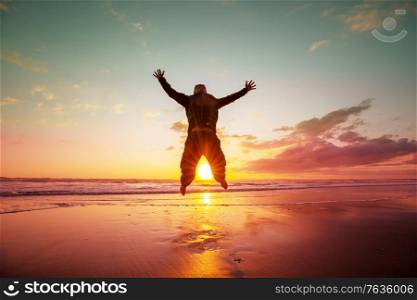 Jumping man on sunset beach