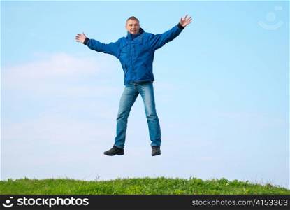 Jumping man on the hill with green grass