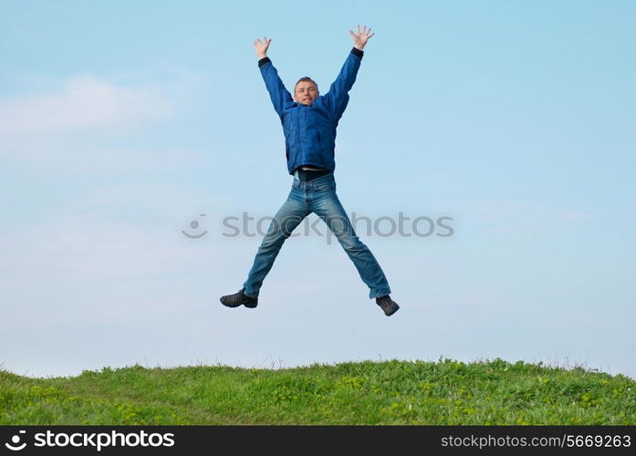 Jumping man on the hill with green grass