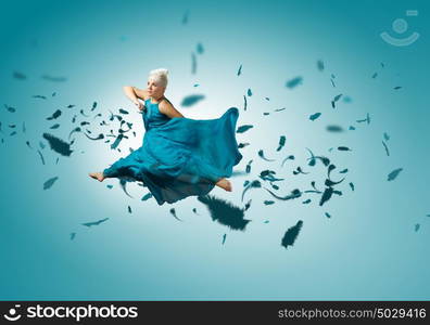 Jumping woman. Young attractive woman in blue dress jumping high