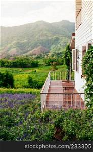 JUN 13, 2013 Thailand : Vintage English country house balcony with chairs and coffee table natural light mountain and flowers field