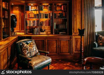 JUN 19, 2011 Serengeti, Tanzania - Luxury African Safari lodge reading room interior with old vintage leather armchairs under warm light and antique books decoration