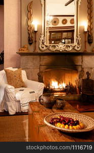 JUN 20, 2011 Serengeti, Tanzania - Luxury African Safari lodge interior with vintage white armchairs wooden table under warm light from fireplace with antique decoration mirror