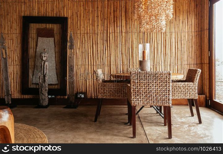 JUN 20, 2011 Tanzania - African Boho contemporary home living room interior with rattan funiture set, pedant lamp, carved wood tribal sculpture and bamboo wall.