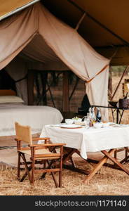 JUN 22, 2011 Serengeti, Tanzania - Luxury Safari tent camp with picnic table in Serengeti Savanna forest Grumeti reserve game drive area - Glamping travel in Africa wild forest