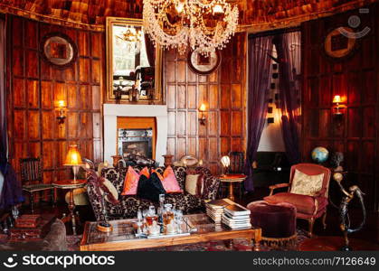 JUN 23, 2011 Ngorongoro, Tanzania - Luxury African tribal cottage living room interior decoration with old vintage colonial style wooden furnitures, armchair, sofa and tables under warm light from grand chandelier