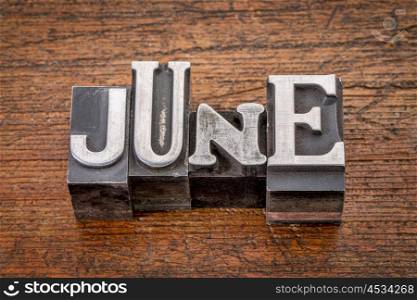 June word in mixed vintage metal type printing blocks over grunge wood