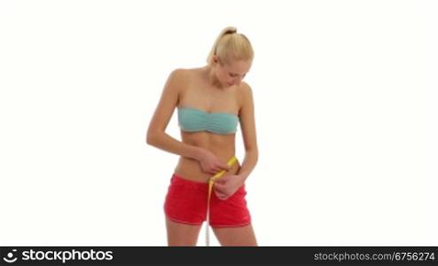 Junge blonde Frau misst ihren Taillenumfang mit einem Massband.Fit young woman in sports wear measuring her waist.