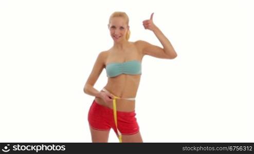 Junge blonde Frau misst ihren Taillenumfang mit einem Massband.Fit young woman in sports wear measuring her waist.