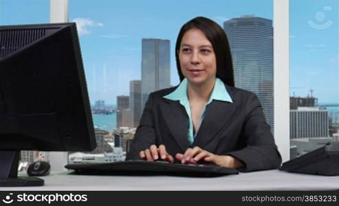 Junge Geschaeftsfrau arbeitet am Computer- Skyline Hintergrund --- Young business woman typing on the computer - skyline background.