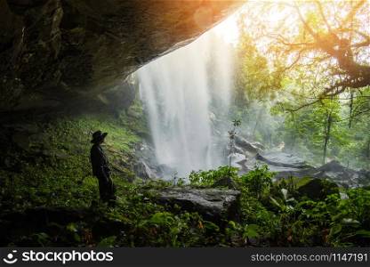 Jungle beautiful waterfall Mountain river stream - Landscape waterfall front of the cave with Trekking man in green forest nature plant tree rainforest with rock stone with sunlight