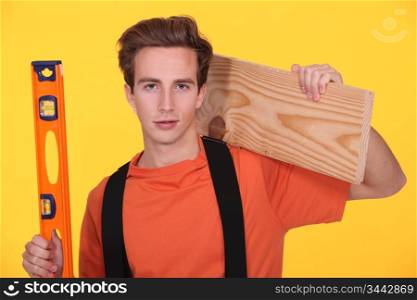 junior carpenter posing with ruler and lumber over shoulder