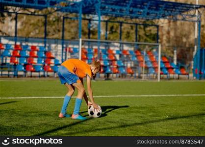 Junior football player placing ball on grass field for free kick or penalty. Professional sport school or training c&for kids. Junior football player placing ball on grass field for free kick or penalty