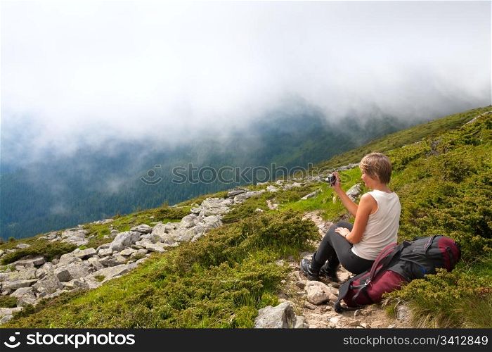 juniper bush and large stones on summer mountainside and woman with camera (Ukraine, Carpathian Mountains)