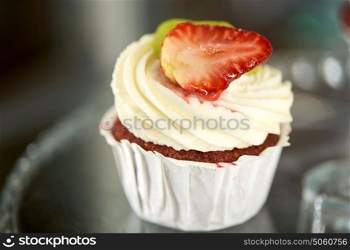 junk food, dessert, baking and pastry concept - close up of cupcake with cream and strawberry. close up of cupcake with cream and strawberry