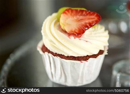 junk food, dessert, baking and pastry concept - close up of cupcake with cream and strawberry. close up of cupcake with cream and strawberry