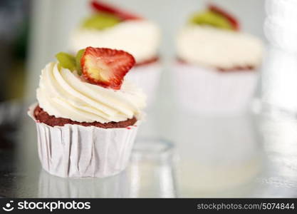 junk food, dessert, baking and pastry concept - cupcake with cream and strawberry at sweet shop. cupcake with cream and strawberry at sweet shop