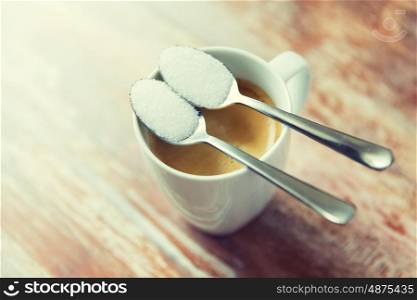 junk-food, diabetes and unhealthy eating concept - close up of white sugar on teaspoon and coffee cup