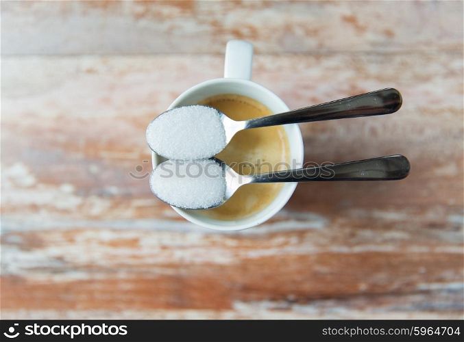 junk-food, diabetes and unhealthy eating concept - close up of white sugar on teaspoon and coffee cup
