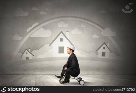 Just like a child. Young funny businessman riding three wheeled bicycle