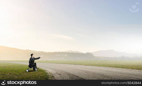 Just like a child. Young funny businessman riding three wheeled bicycle