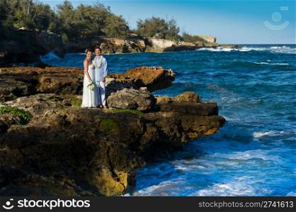 Just Married. Beautiful young couple on a rocky beach on their wedding day.
