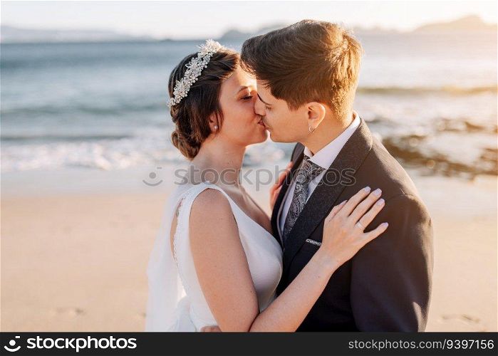 Just married couple kissing at the beach at sunset