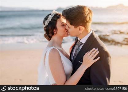 Just married couple kissing at the beach at sunset
