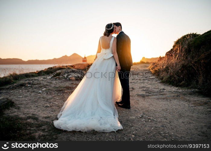 Just married couple kissing near the ocean at sunset