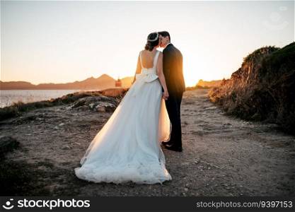 Just married couple kissing near the ocean at sunset