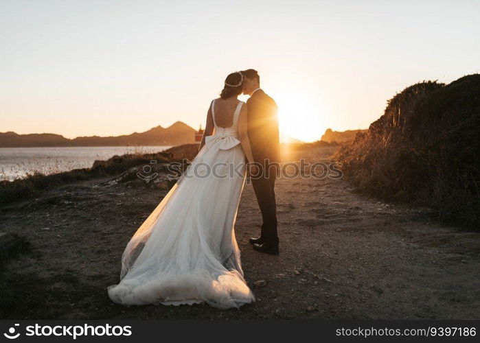 Just married couple kissing near the ocean at sunset