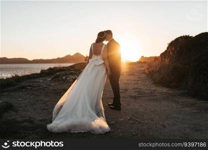 Just married couple kissing near the ocean at sunset