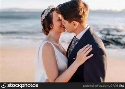 Just married couple kissing on a beach at sunset
