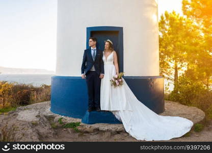 Just married couple on the door of a lighthouse at sunset