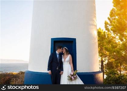 Just married couple on the door of a lighthouse at sunset