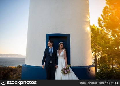 Just married couple on the door of a lighthouse at sunset