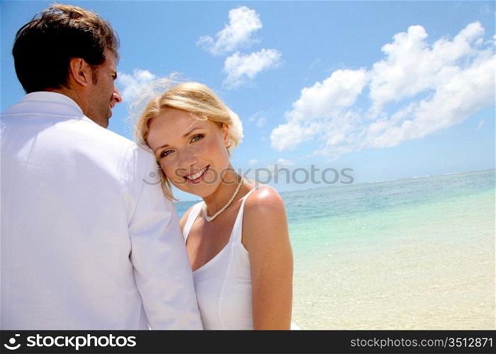 Just-married couple standing by blue lagoon