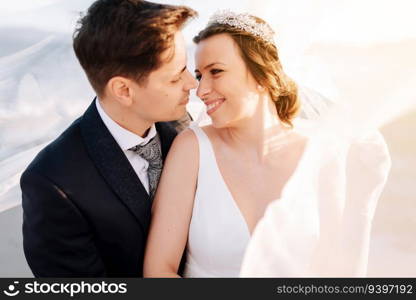 Just married couple under the bride veil at sunset