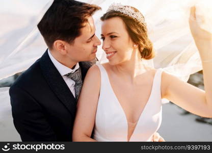 Just married couple under the bride veil at sunset