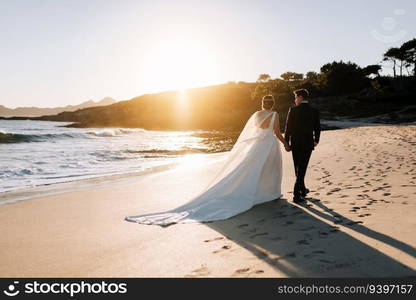 Just married couple walking by the beach at sunset