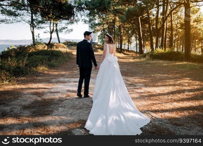 Just married couple walking by the woods with their back to the camera